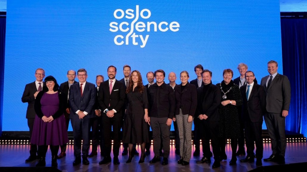 Group of people on a stage in front of blue screen saying "Oslo Science City".
