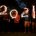 The number 2021 in sparkling light held by four persons we can hardly see