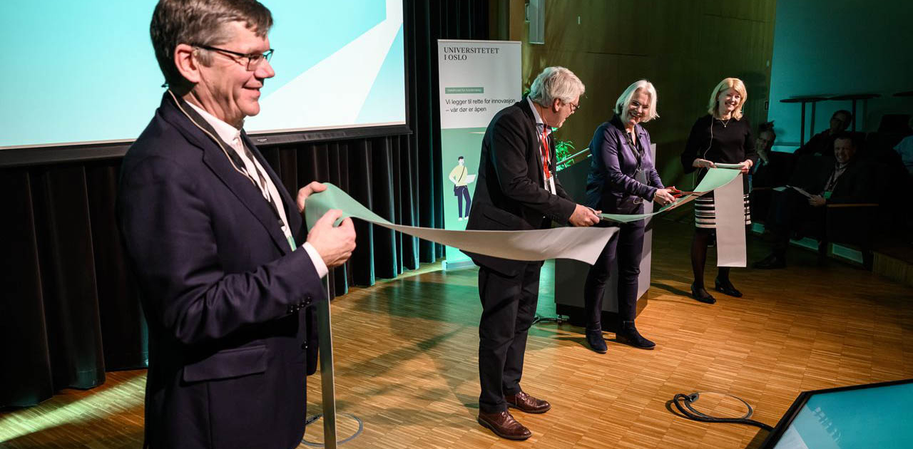 Four people on a stage cutting a ribbon