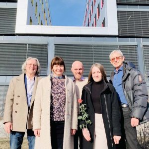 5 people in front of a modern building in sunshine